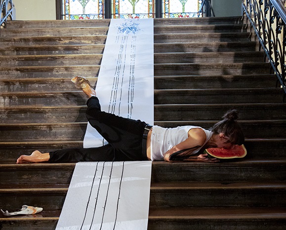 Eine Frau lieget im Rahmen einer Kunst-Performance auf einer Treppe.